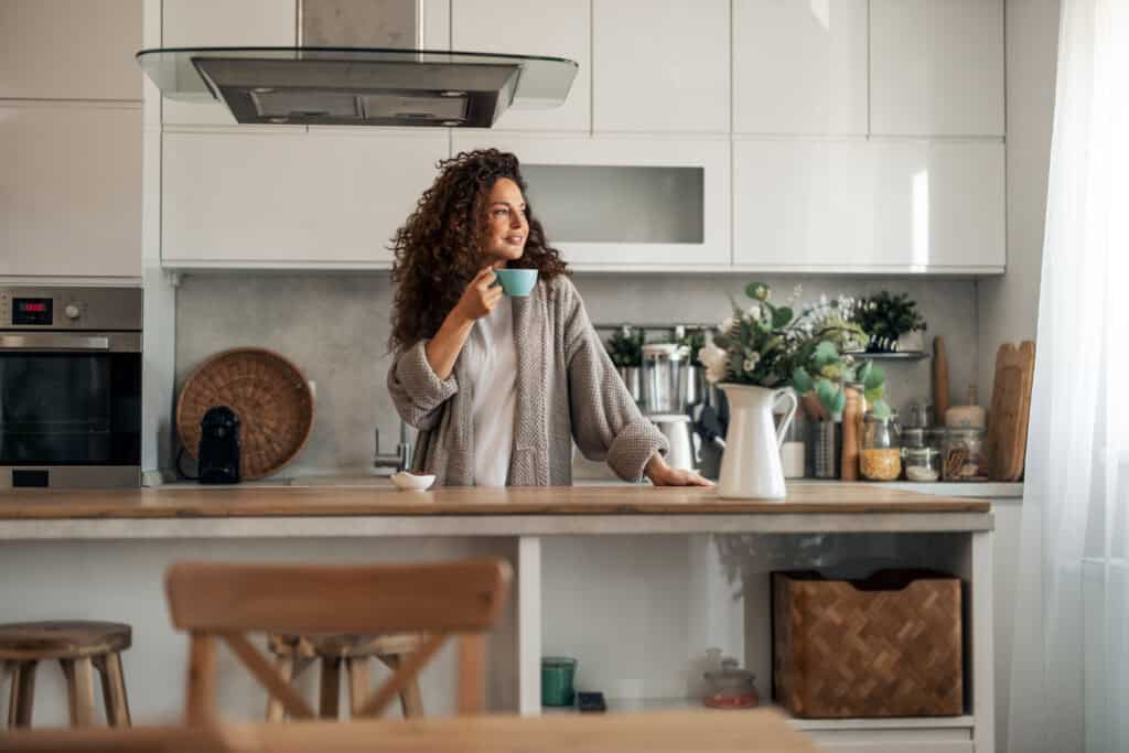 Woman enjoying a healthy morning coffee in a modern kitchen setting.